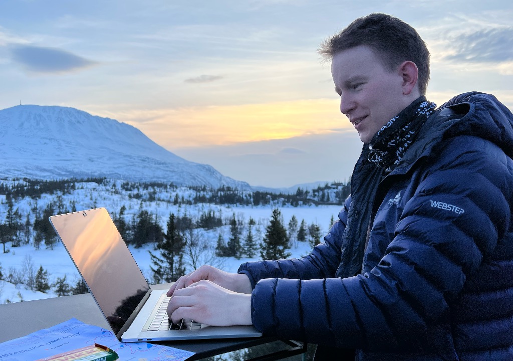 Stig Baugstø jobber med PC-en ute, med boblejakke på. Gastatoppen i bakgrunnen.